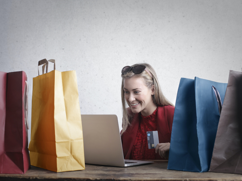 A woman using her credit card while being surrounded by paper bags