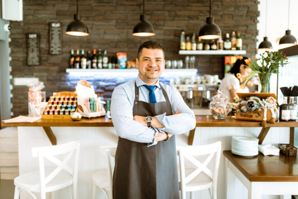 Man in apron crossing arms in a cafe