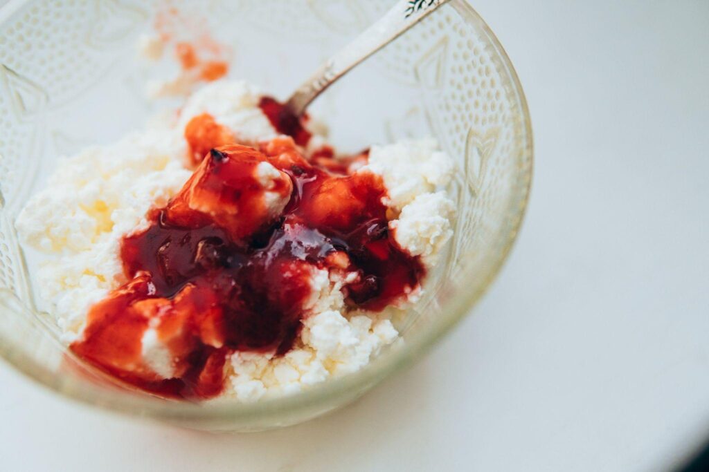 Cottage cheese in glass bowl with strawberry syrup