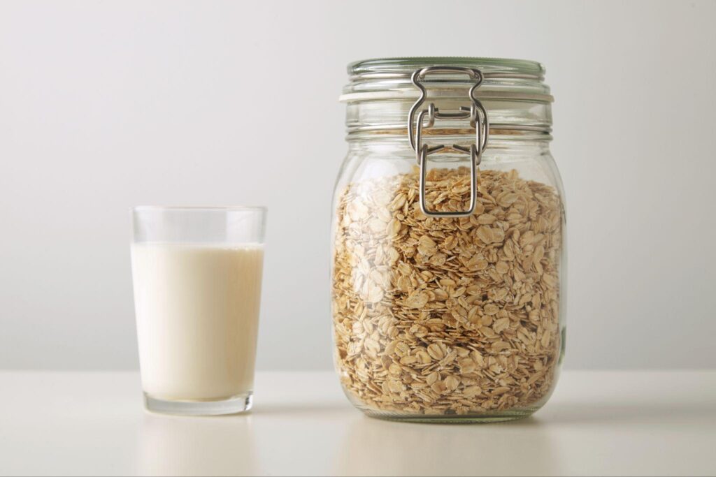 Oats in a glass jar with a glass of milk on counter space