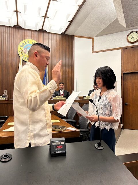Rod Daus-Magbual taking oath, with raised hand, before daughter