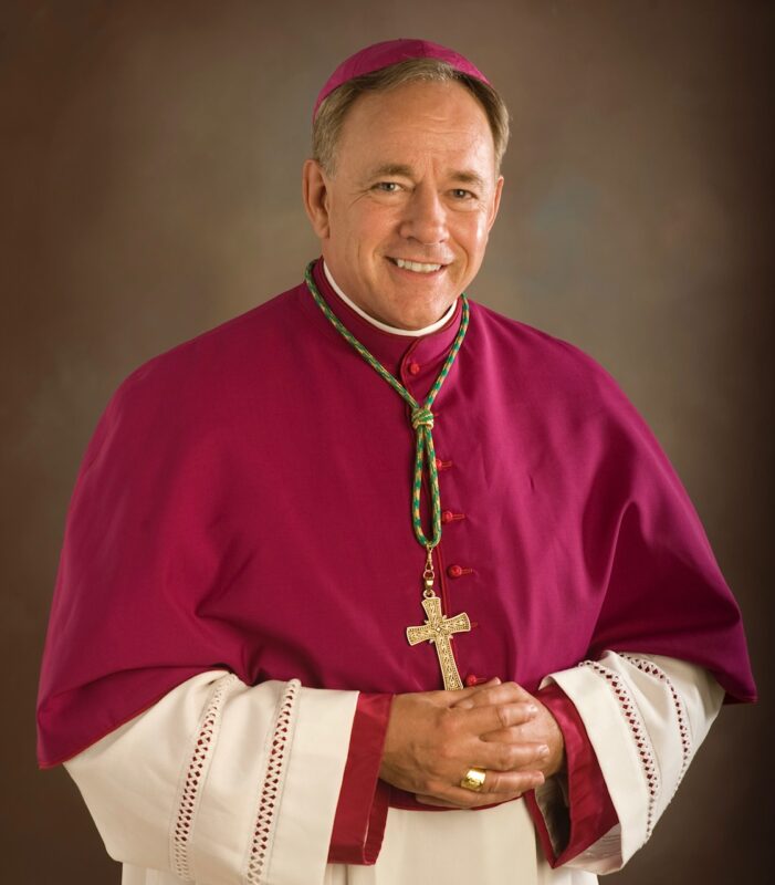 Vancouver Archbishop wearing maroon vestment and cross pendant