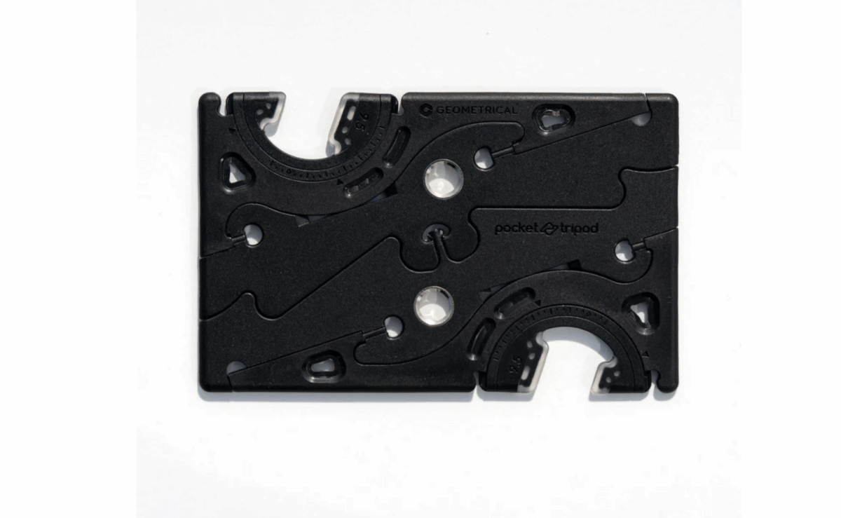 Pocket Tripod PROv2 folded to credit-card size next to a phone mounted in tripod mode.