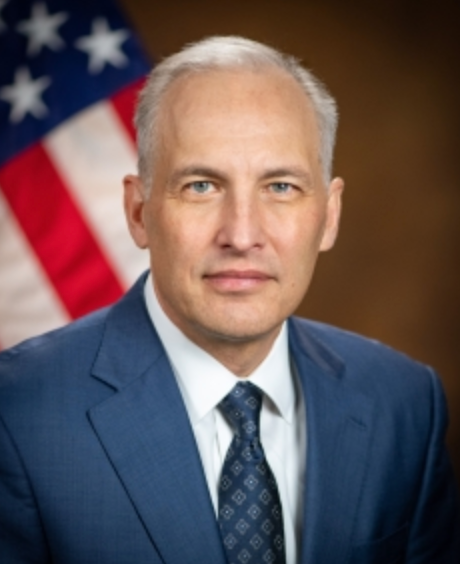 Headshot of Assistant Attorney General Matthew G. Olsen wearing a suit with flag in background