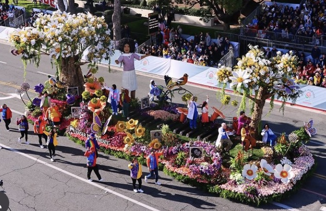 Rose Parade float bedecked with flowers, with people dancing