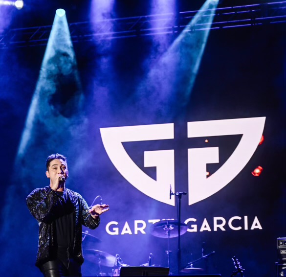 Garth Garcia on stage with his logo and name in the background