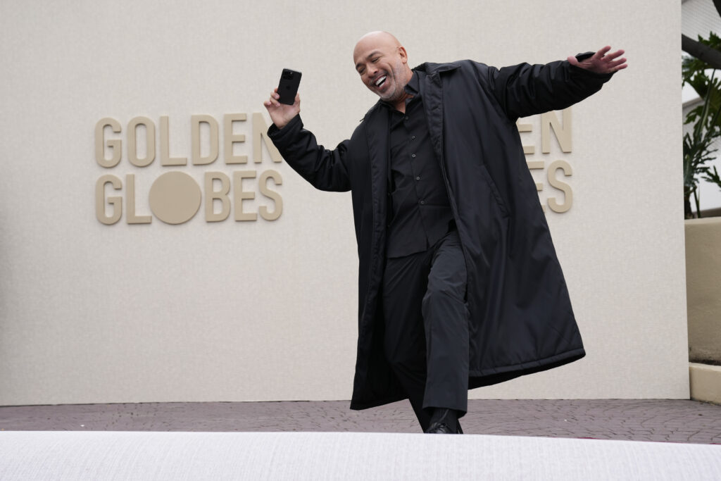 Jo Koy in a black suit in front of Golden Globes signage