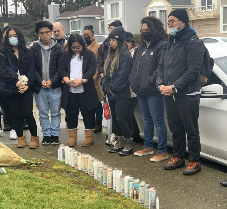 Family and friends say prayers, with candles on the ground