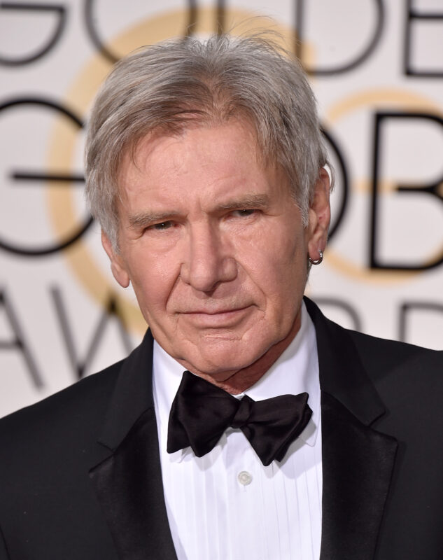 headshot of harrison ford in black suit with bow tie