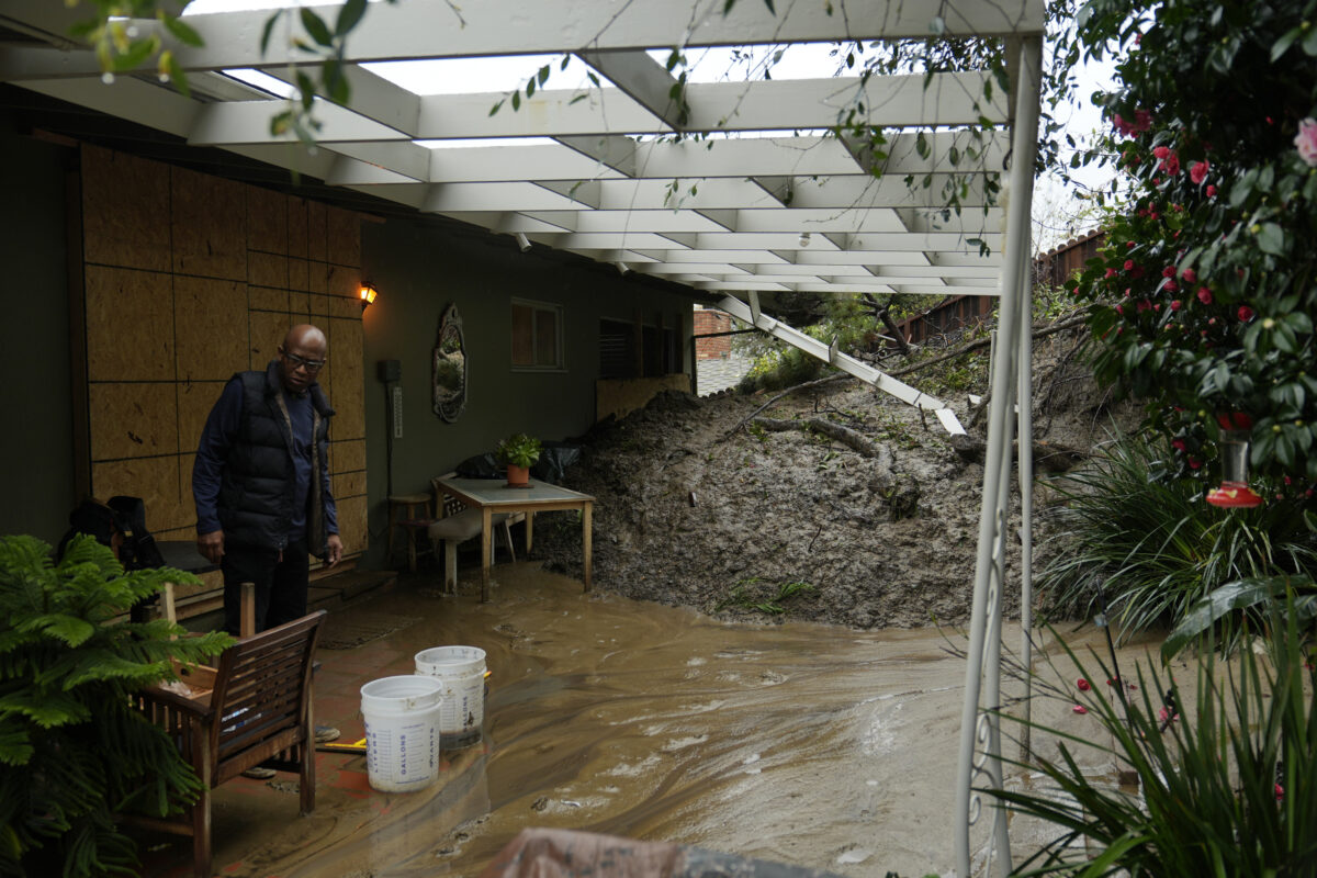 Man in flooded patio with mud and debris