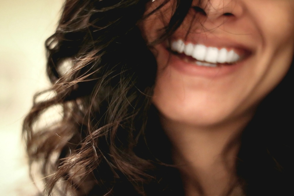 A woman shows her teeth as she smiles for story: Oral health and mental health are more connected than you think