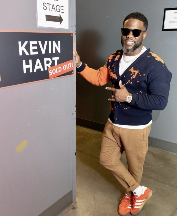 Kevin Hart wearing sunglasses next to sign with his name