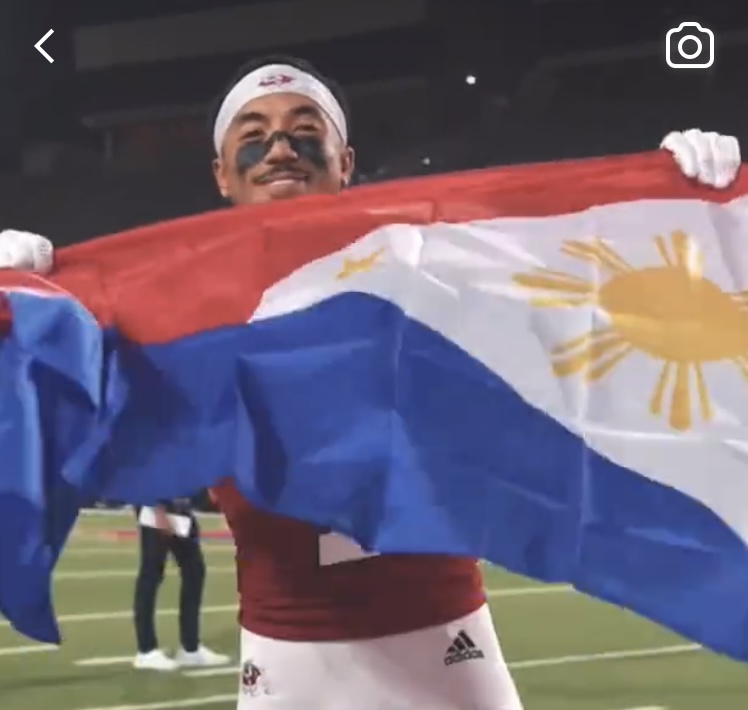 Nikko Remigio holding up a Philippine flag