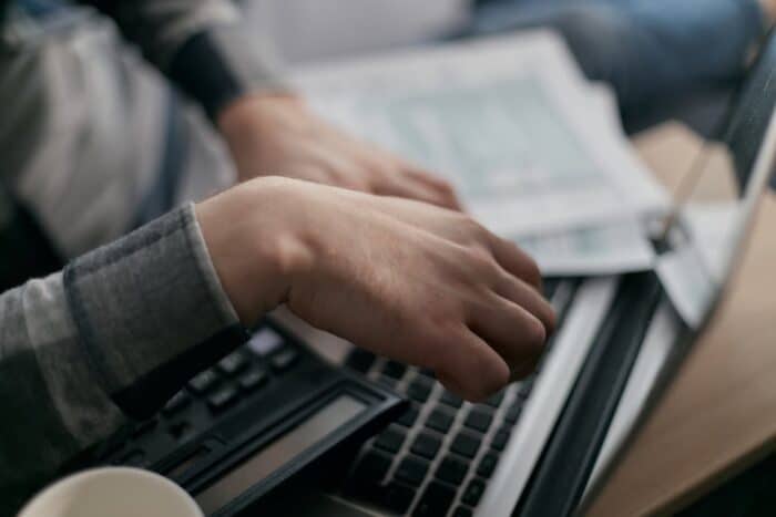 Person calculating finances with a calculator and pen, representing debt consolidation and financial planning.