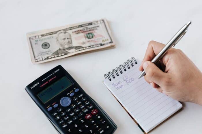 Person using a calculator and notepad for budgeting and financial planning, symbolizing debt management and relief strategies.