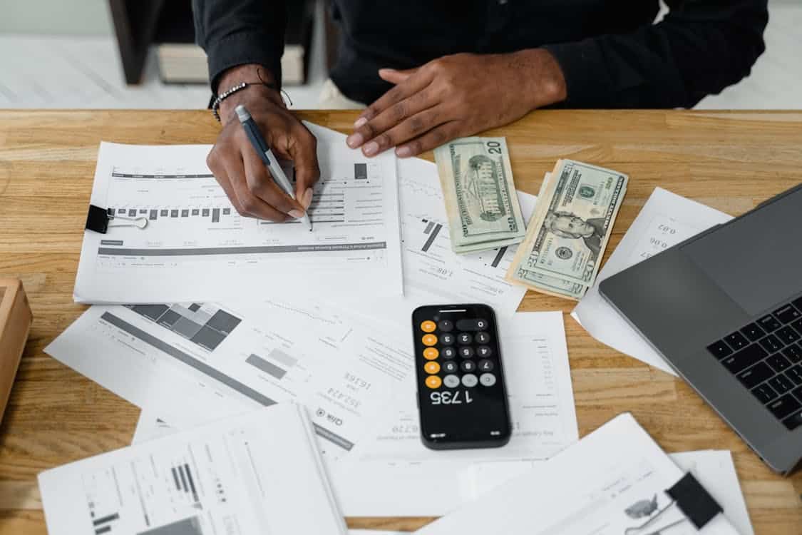 Hands working on budgeting with bills, calculator, and financial documents spread on a table