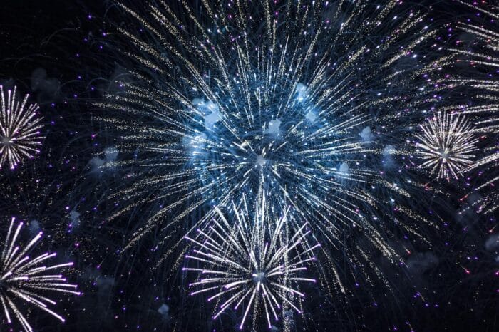 Brilliant fireworks exploding in the night sky with vibrant blue and white bursts, symbolizing festive celebrations and joy.