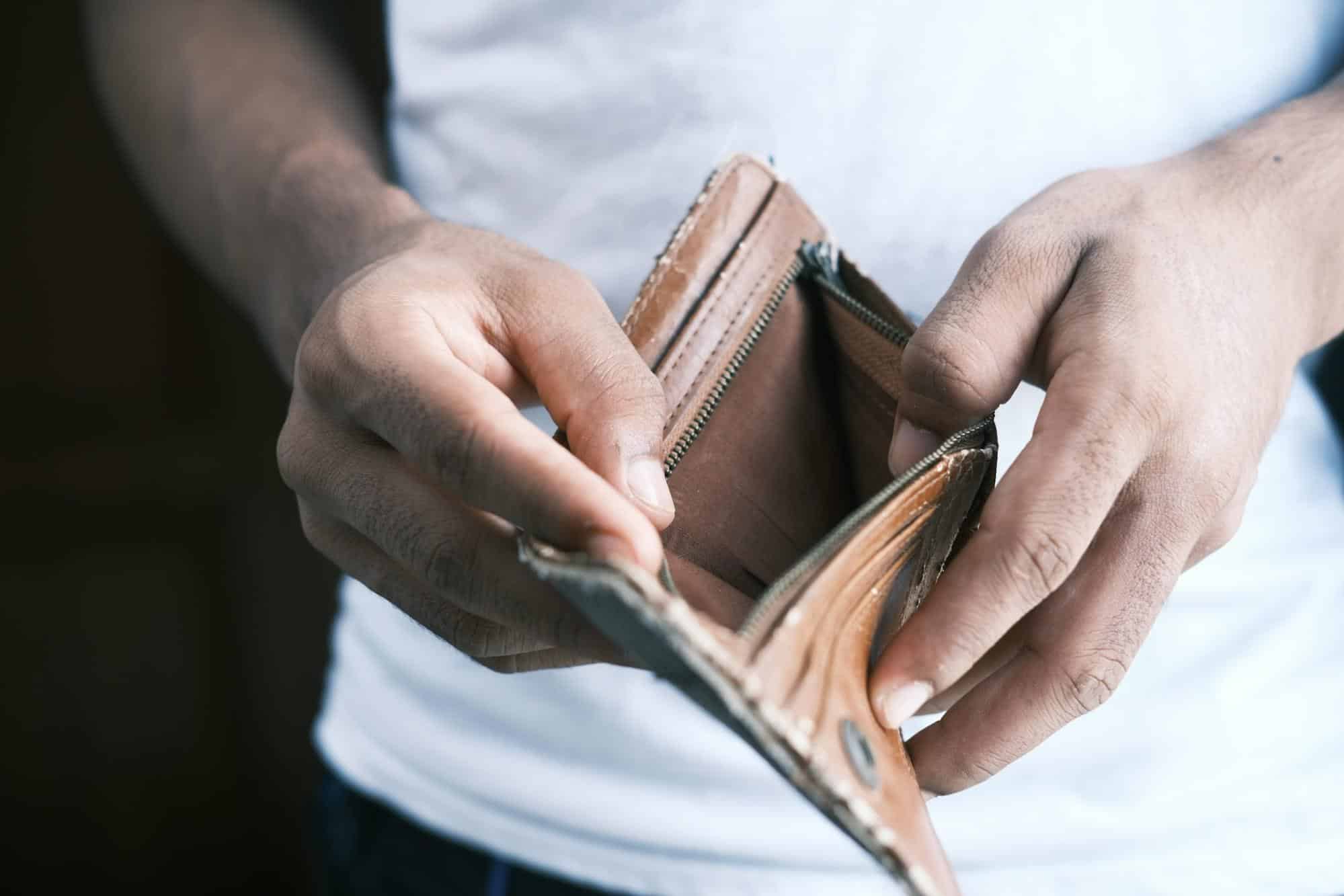 Close-up of a person holding an empty wallet, illustrating financial hardship in the context of CuraDebt's debt settlement and tax relief services.