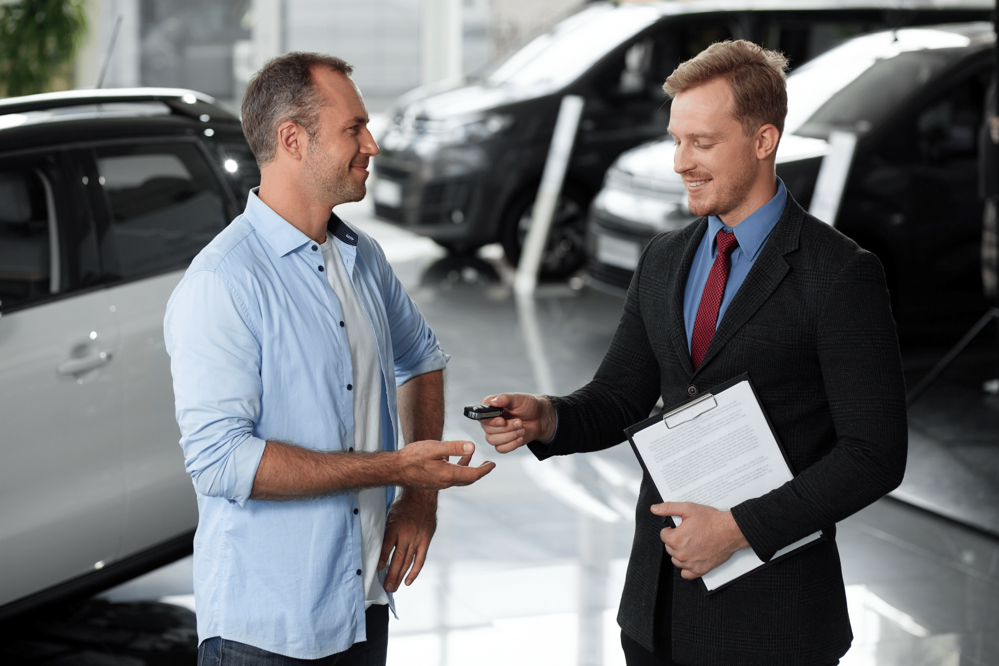 Car dealer handing over car keys to a customer at a car dealership, highlighting vehicle acquisition through auctions.