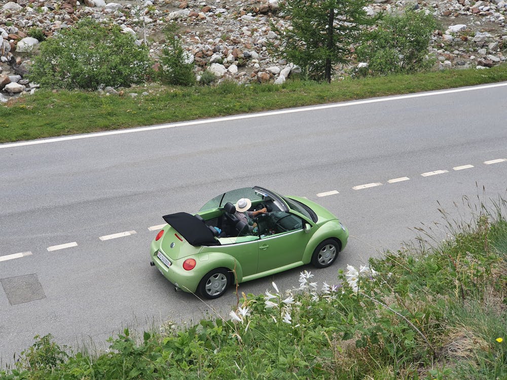 Person driving a green convertible on a scenic road, featured in a section explaining the application and approval process for Capital One Auto Financing, including pre-qualification steps and document requirements.