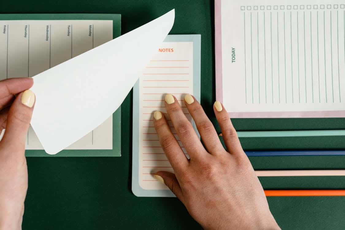 Close-up of a person organizing notes and documents on a desk, used in a section detailing the eligibility criteria for Capital One Auto Loans, including age, income, credit score, and required documents.