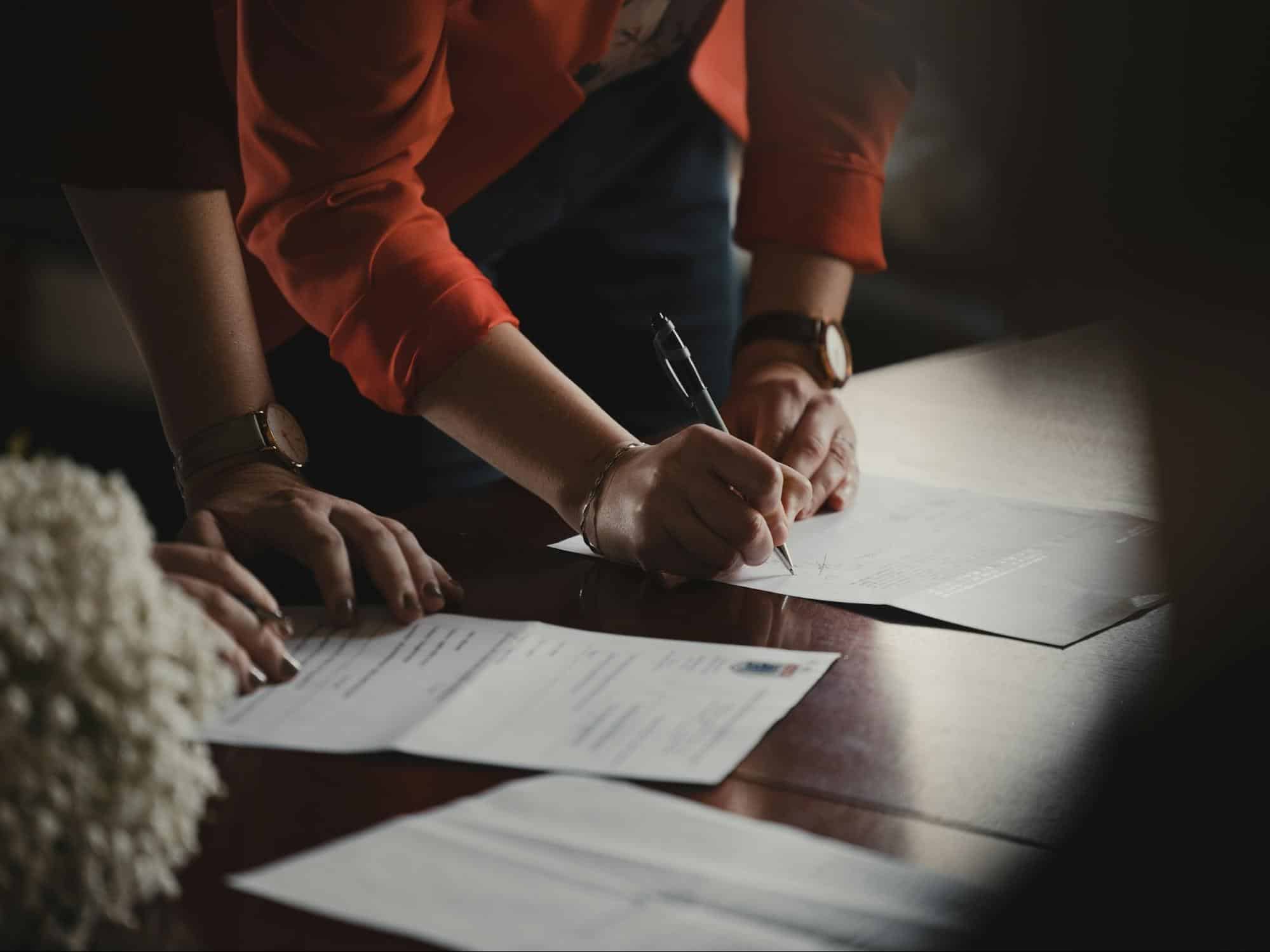 Person filling out loan application paperwork, representing the Fig Loans application process and eligibility requirements.