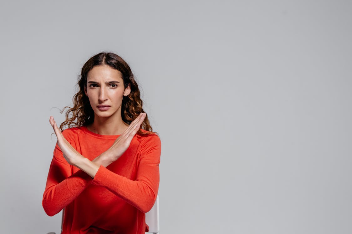 Woman making an 'X' gesture with her arms, symbolizing the drawbacks and disadvantages of Fig Loans.