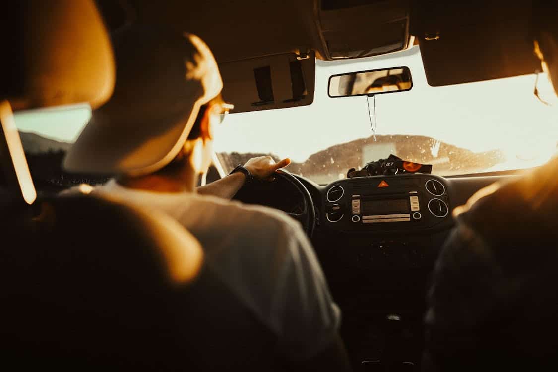 View from the backseat of a car during sunset, showing a driver on the road, featured in a section offering final advice on comparing auto loan providers and making an informed decision when considering Capital One Auto Finance.