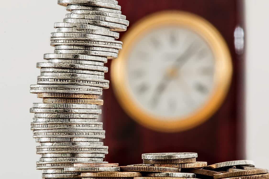 Stacked coins in front of a blurred clock symbolizing the high interest rates and time-sensitive nature of loan repayments with subprime lenders like Republic Finance