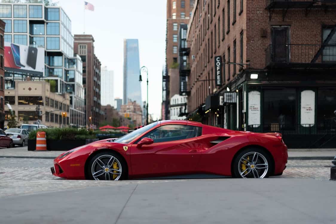 Red Ferrari parked on a city street, used in an article section explaining Capital One Auto Finance's services including pre-qualification, used car loans, refinancing, and account management.