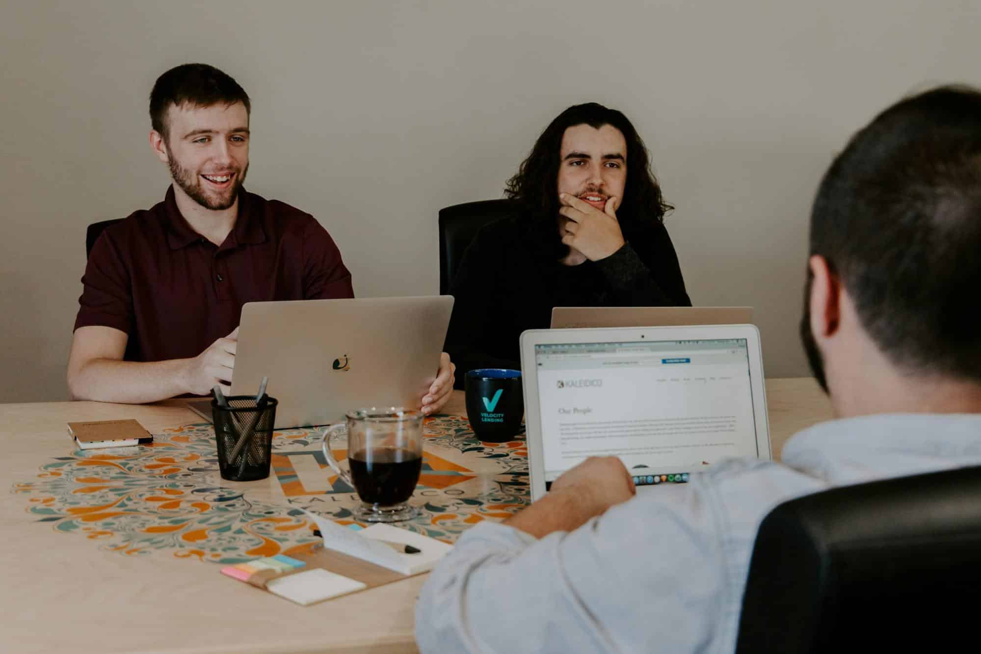Group of people discussing customer reviews while looking at laptops, symbolizing the evaluation of Republic Finance's loan services and borrower feedback