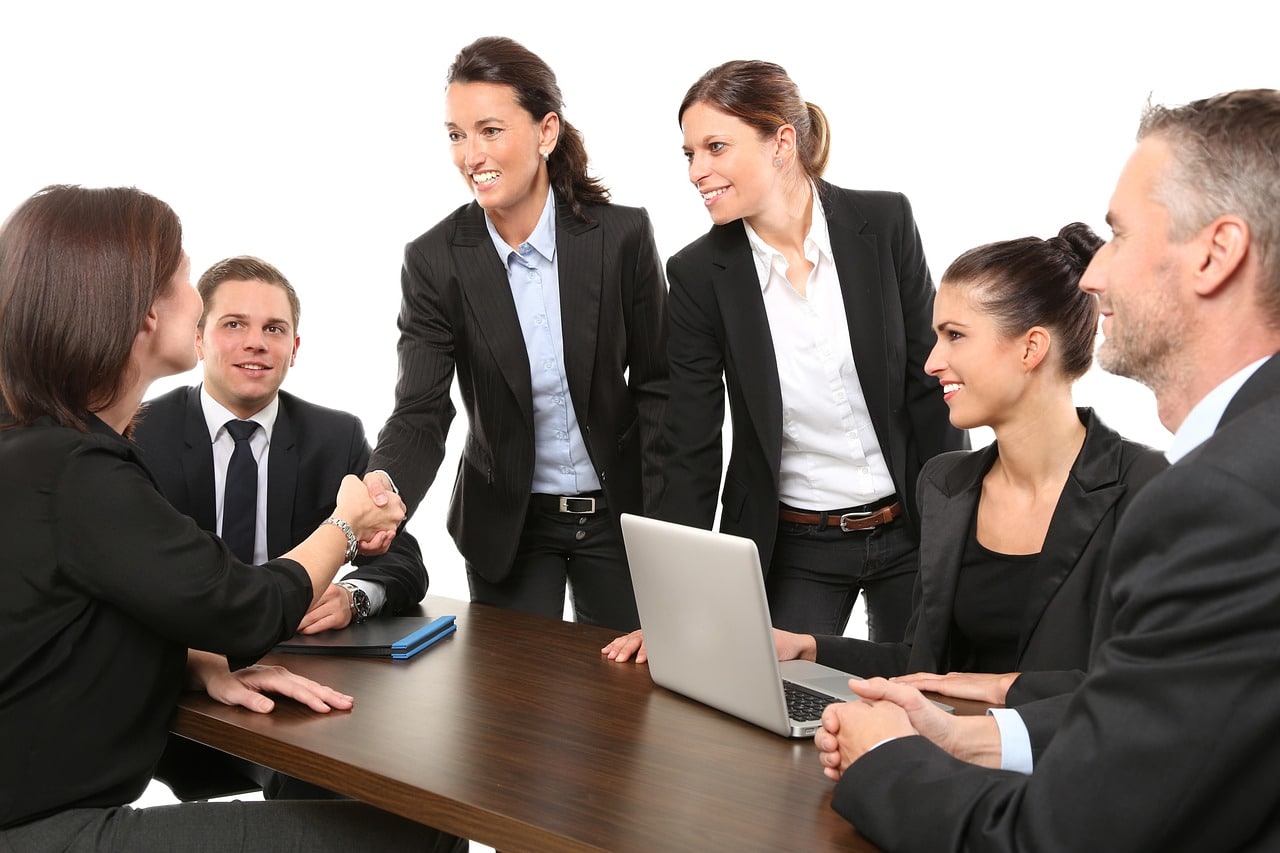 Group of business professionals in a conference room shaking hands and smiling, symbolizing Alleviate Financial Solutions’ client support and collaborative approach to debt relief services.