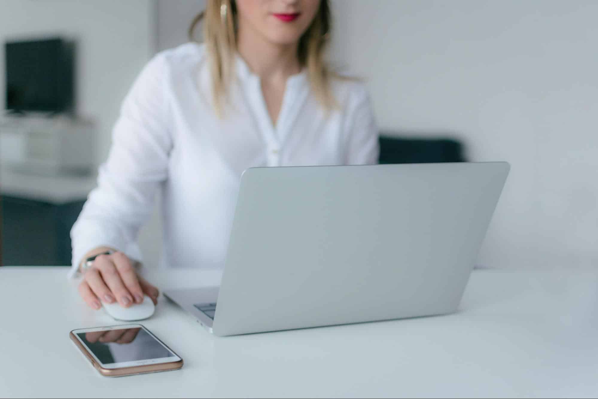 Close-up of a woman using a laptop with a smartphone nearby, representing the online application process for Alleviate Financial Solutions’ debt settlement consultation.