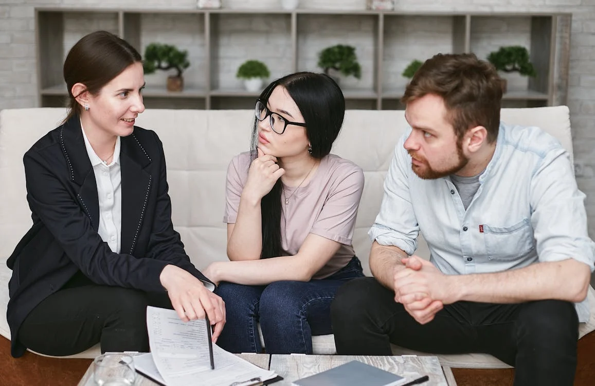 Business consultant meeting with two clients on a couch, discussing documents—used to illustrate Better Rise Capital’s emphasis on personalized support and customer satisfaction.