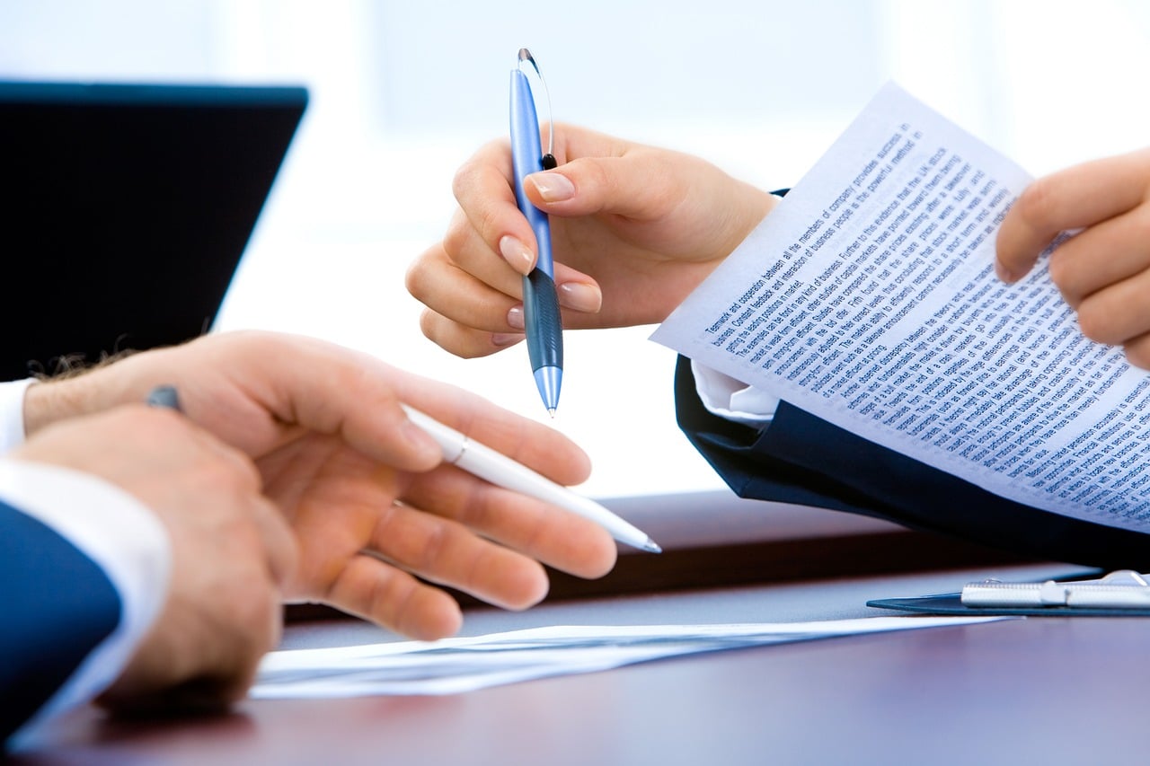 Close-up of two people exchanging pens and signing a credit agreement document, representing the final step in securing a CreditFresh line of credit.