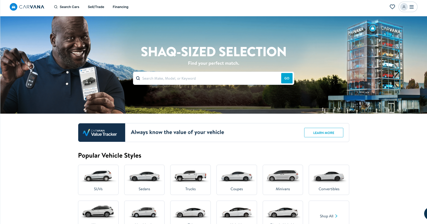 Screenshot of the Carvana website featuring Shaquille O'Neal holding a car key and a smartphone. The header reads "Shaq-Sized Selection" next to an image of a blue glass car vending machine tower.