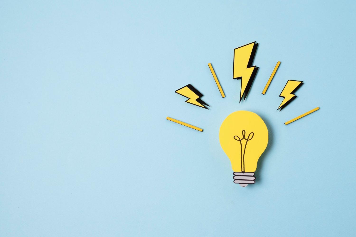 A yellow paper-cutout lightbulb with black lightning bolt symbols on a light blue background, representing creative ideas and content innovation.