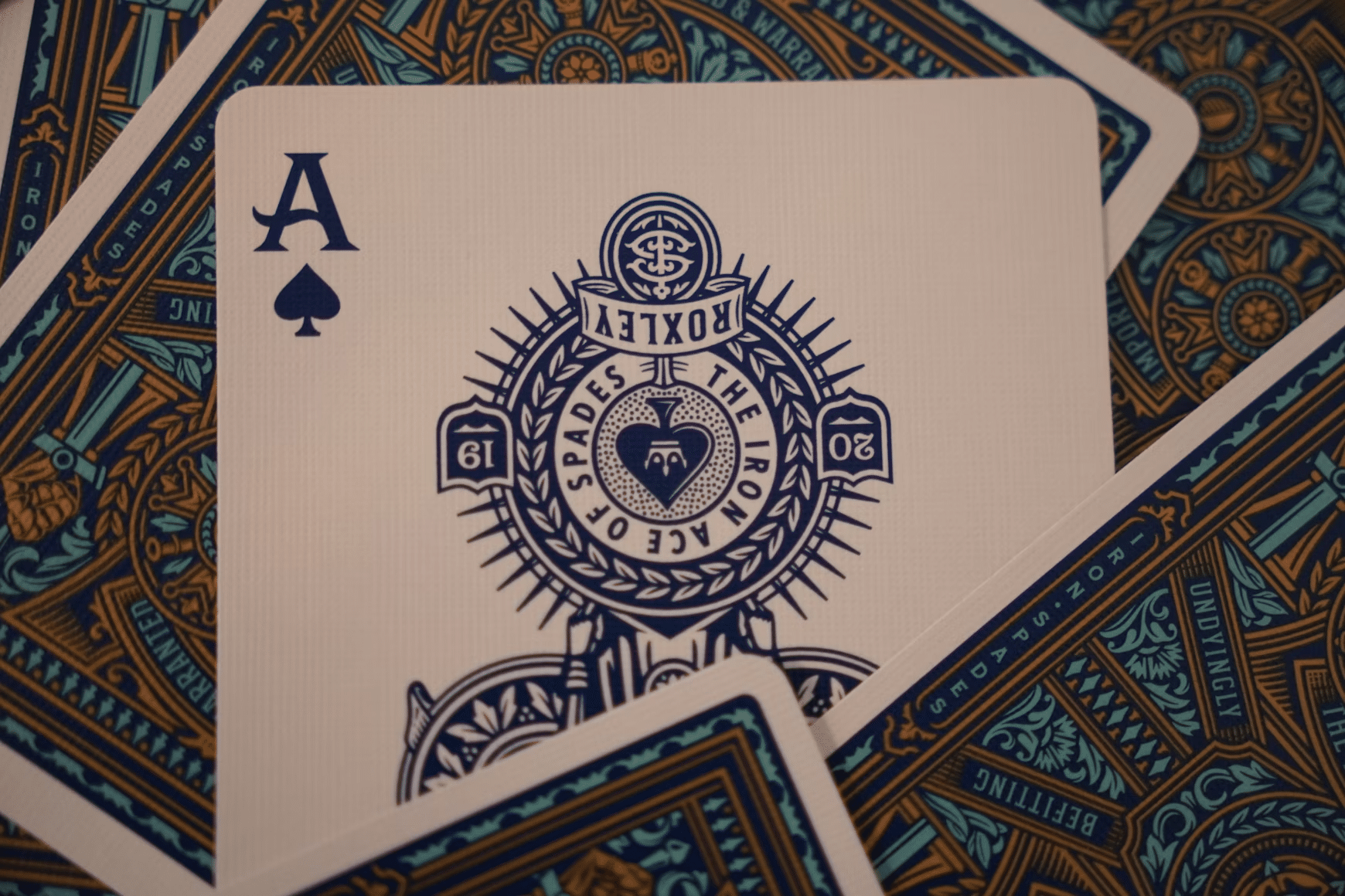 Close-up of an ornate Ace of Spades playing card from the Roxley deck, with decorative card backs fanned out underneath, illustrating high-stakes card games and the premium online casino experience.